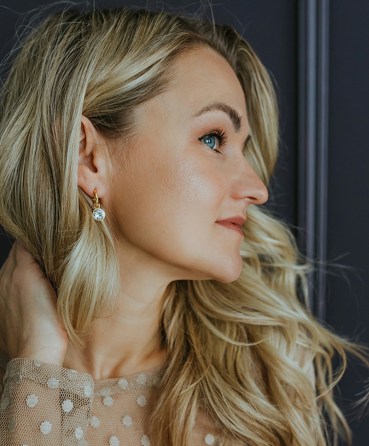 Woman with blonde hair and earrings, profile view.