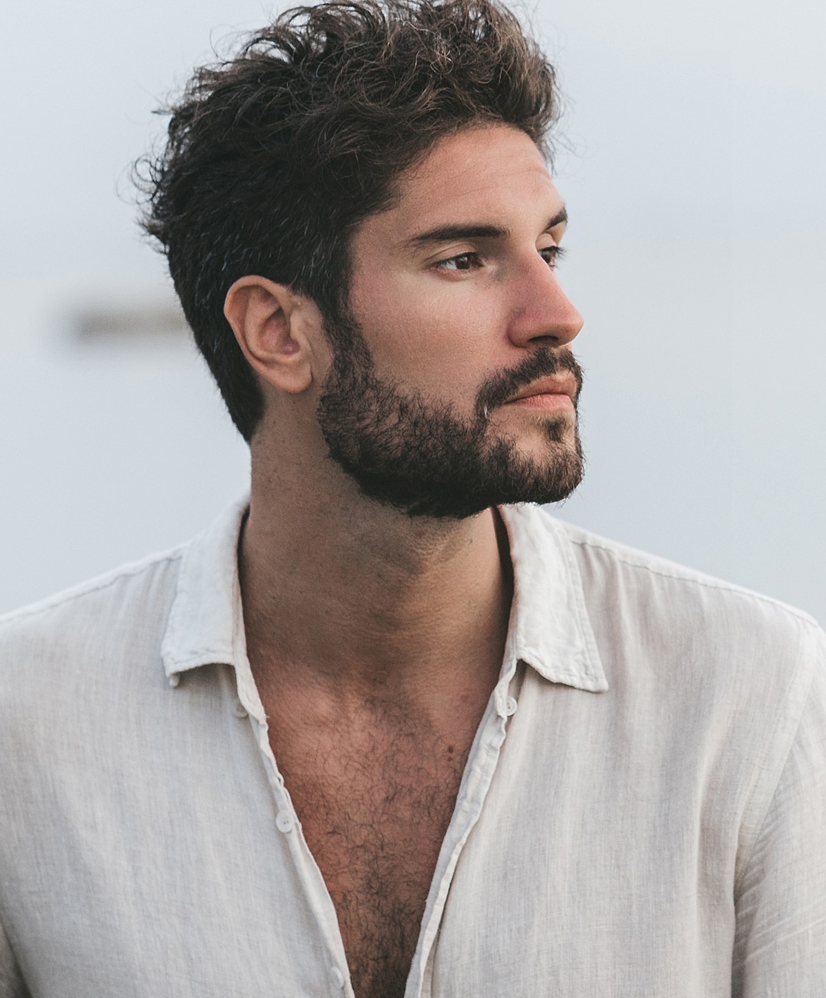 Man with beard in casual shirt outside.