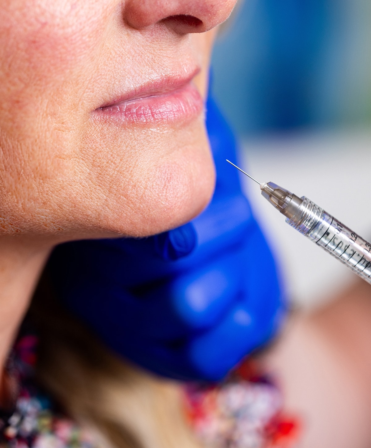 Cosmetic procedure with syringe near woman's face.