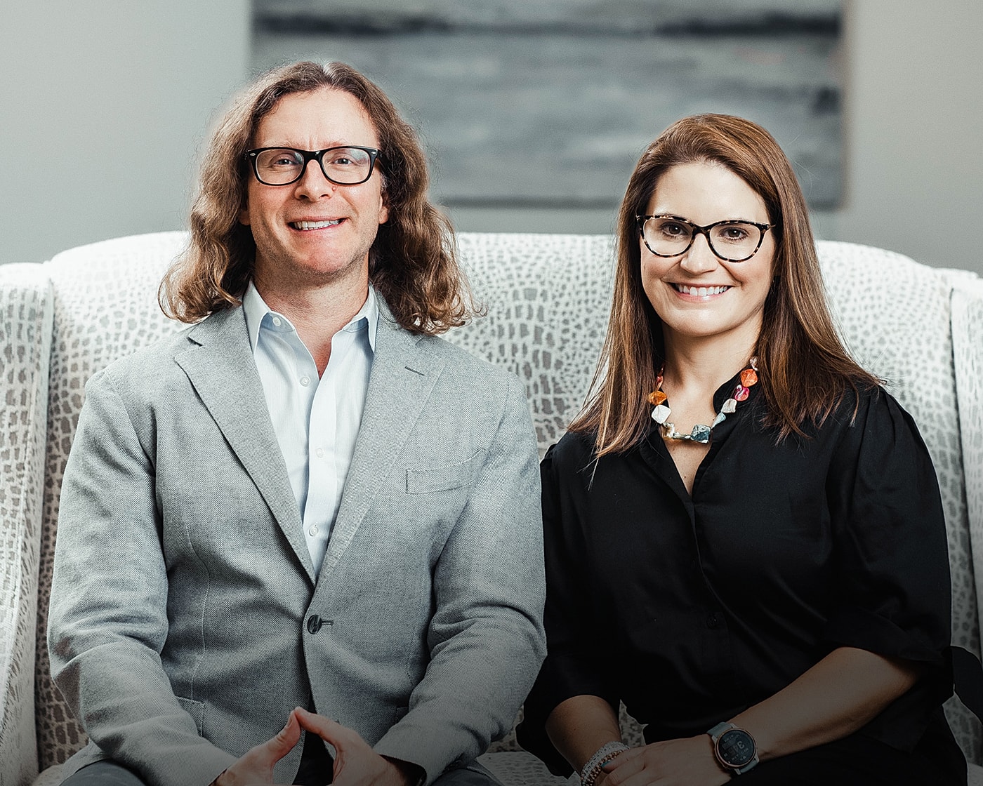 Professional couple posing on stylish chairs.