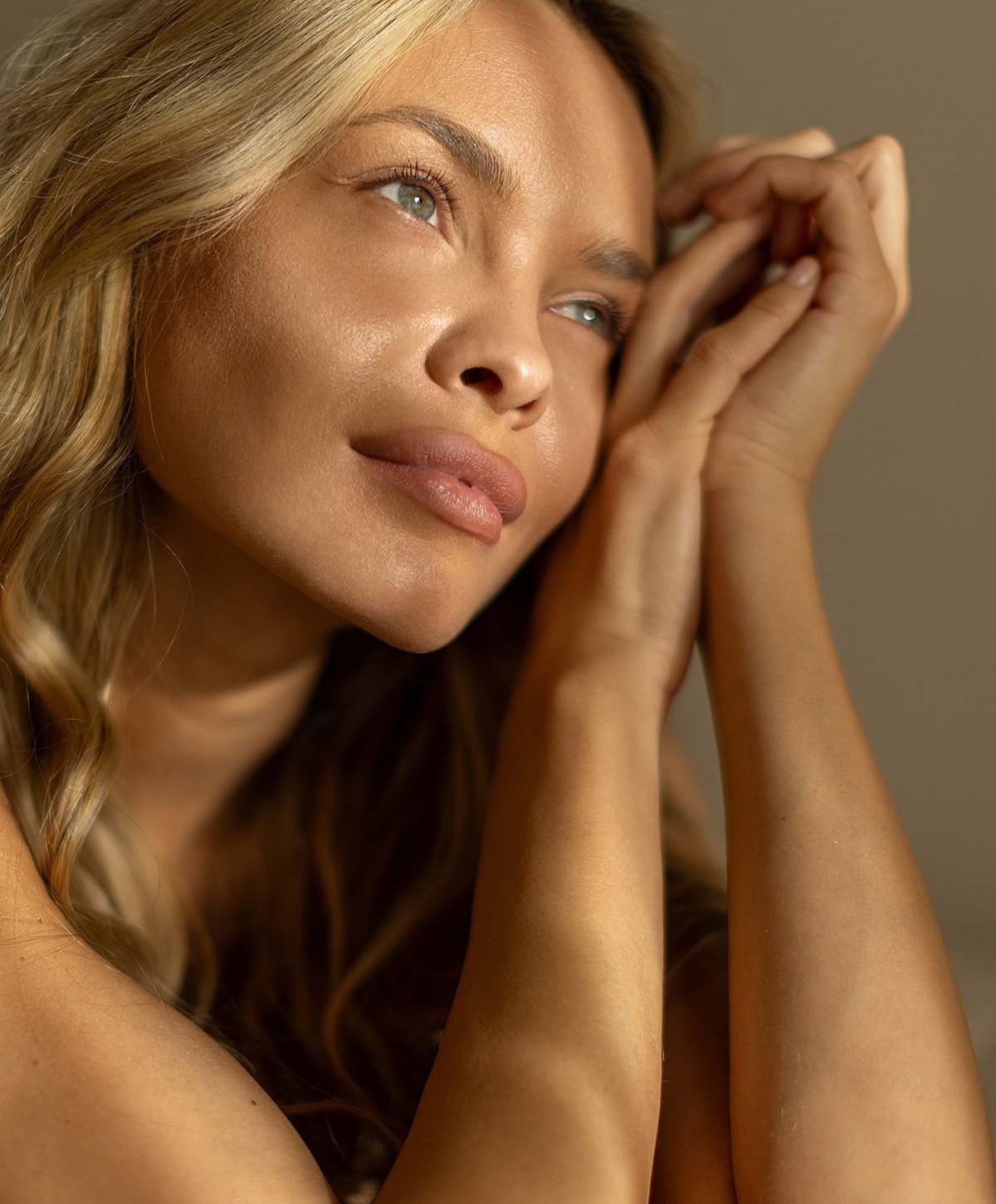Woman looking thoughtfully with hands clasped.