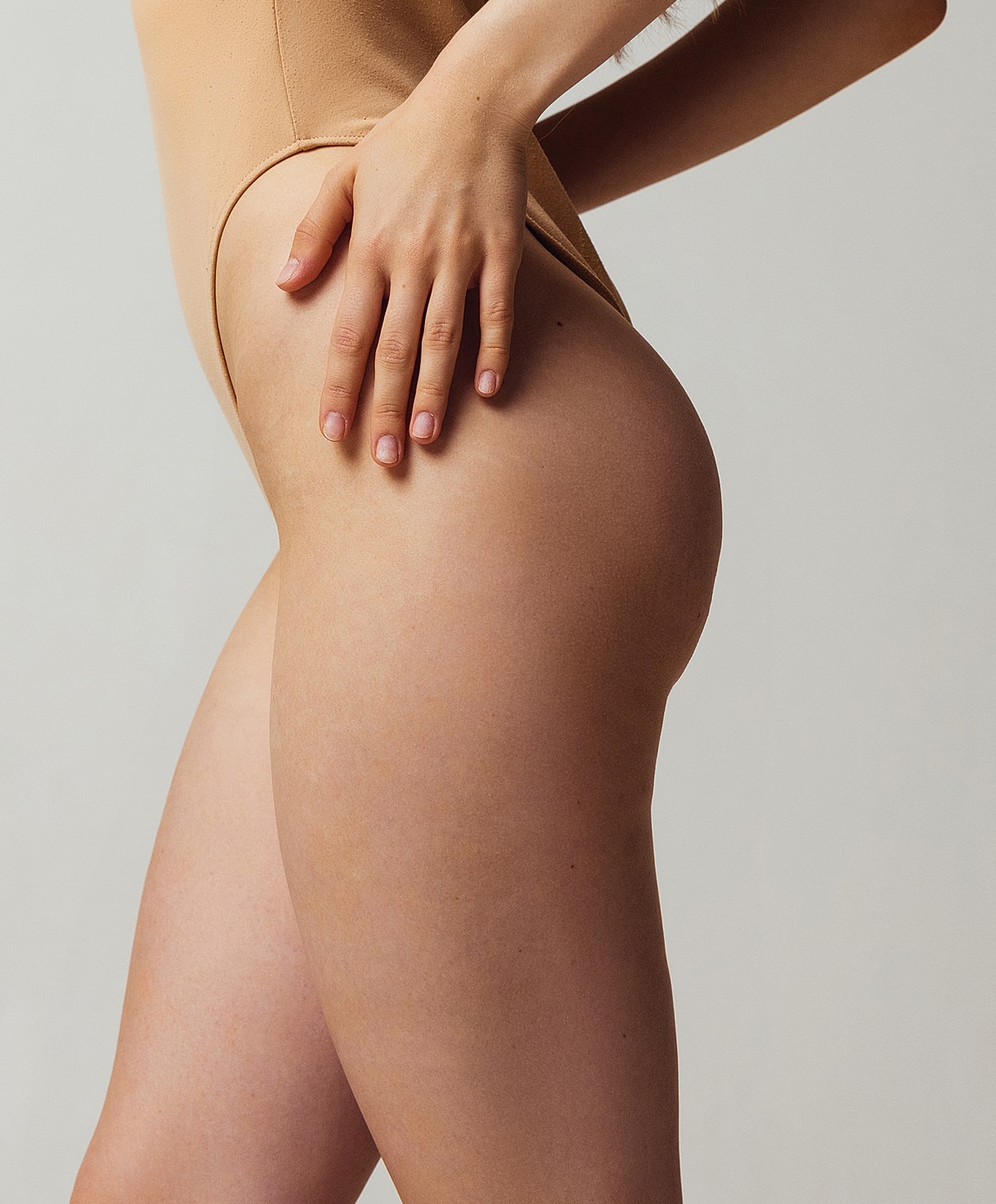 Model posing in fitted bodysuit, side view.