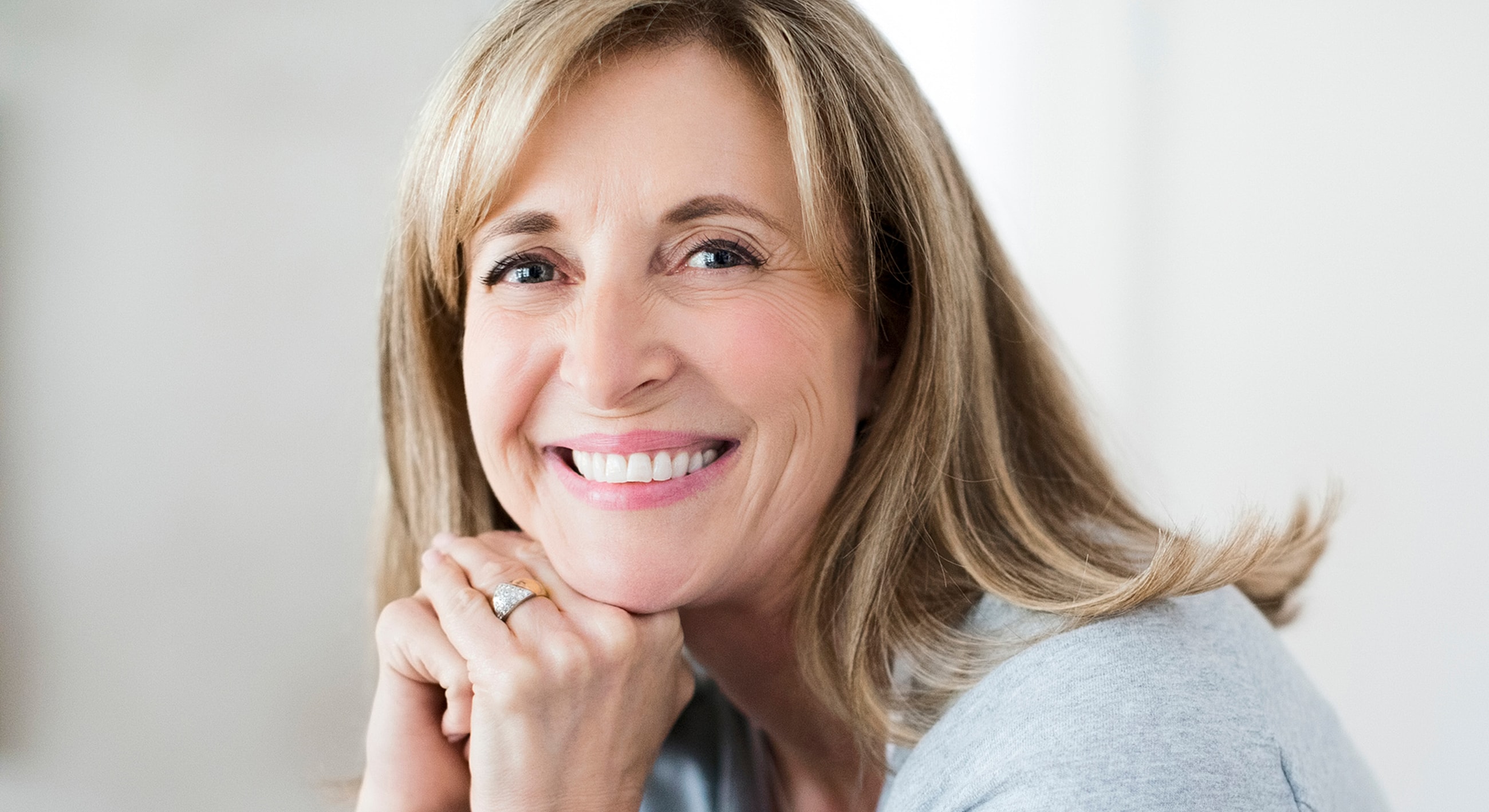 Smiling woman resting her chin on hands.